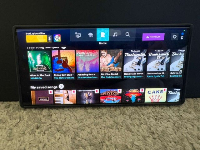 Phone in landscape showing Rocksmith+ home screen with song carousels during user testing